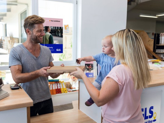 A woman and her child pick-up a parcel from a GLS Parcel Shop