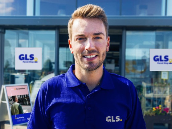 A GLS employee stands before a GLS Point