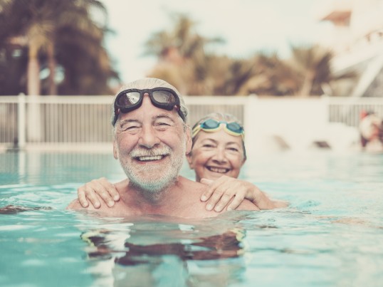 A smiling elderly couple in a swimming pool