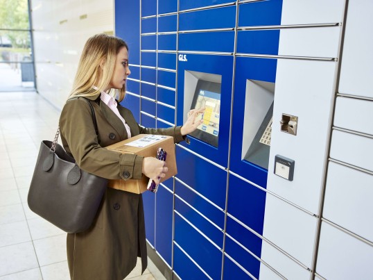 A woman stands at a GLS Parcel Locker