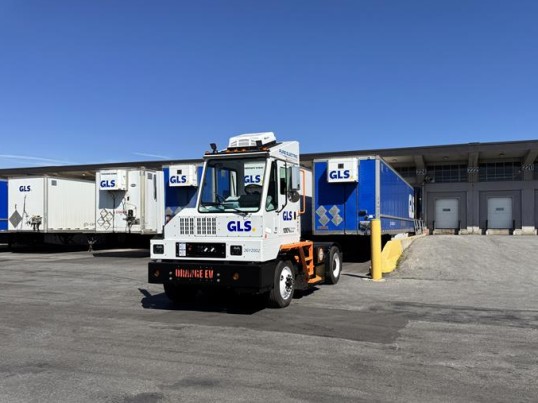 Orange electric shunt truck in front of a GLS terminal.