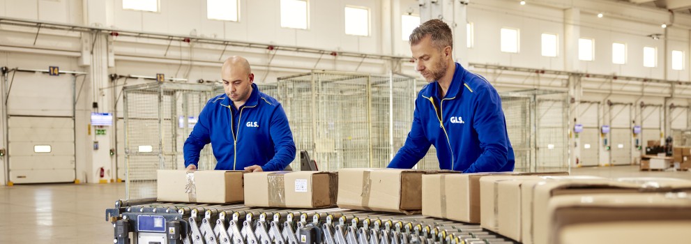 Two employees sorting packages on a conveyor