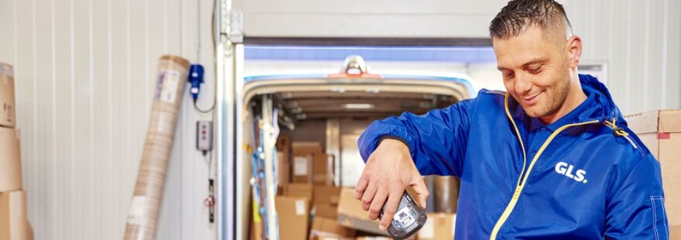 Man in GLS uniform scanning box in front of van filled with parcels
